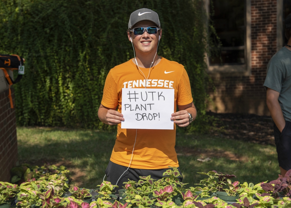 A student poses with a sign that says, "# UTK Plant Drop," for the event that gave thousands of free plants away.
