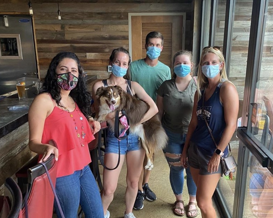 The officers and Tracy Hawk's dog pose with their masks on at a local rooftop bar