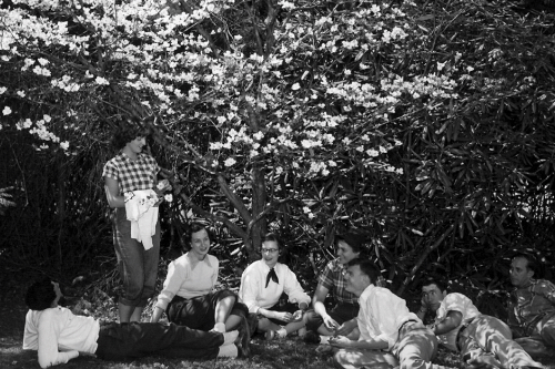 An antique black and white photograph of a group of young people sitting under a dogwood tree.