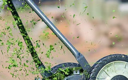 Close up of a manual push mower mowing grass