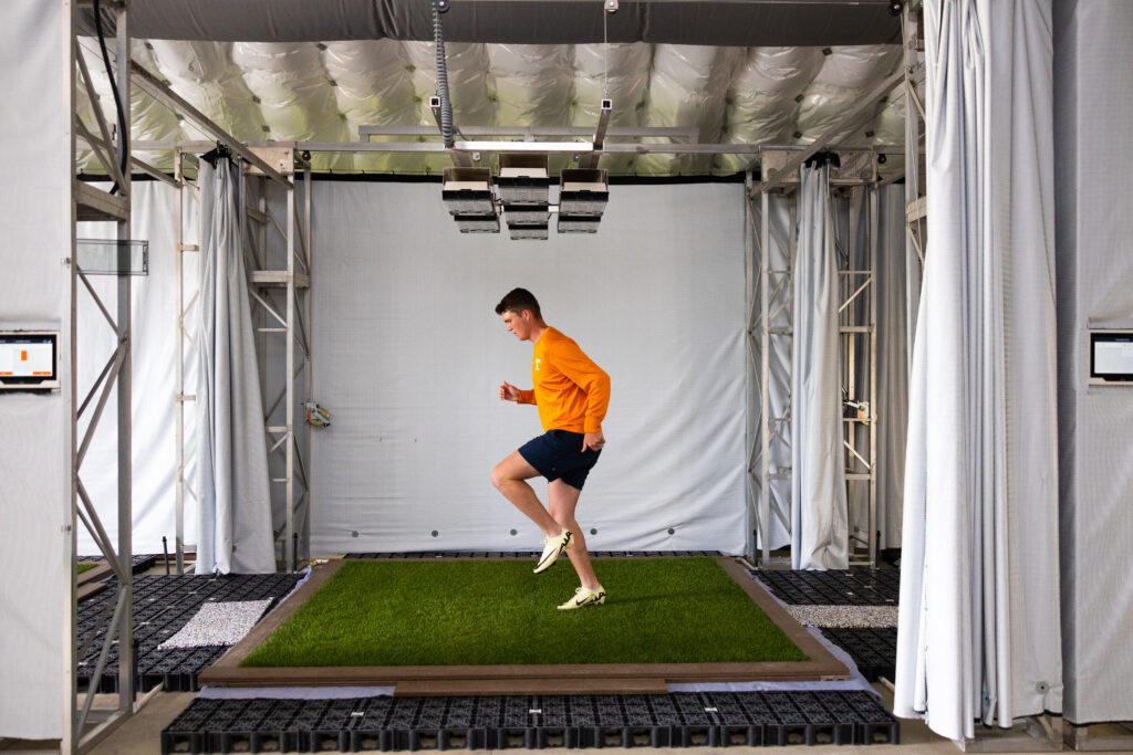 Student running on turfgrass in a research facility