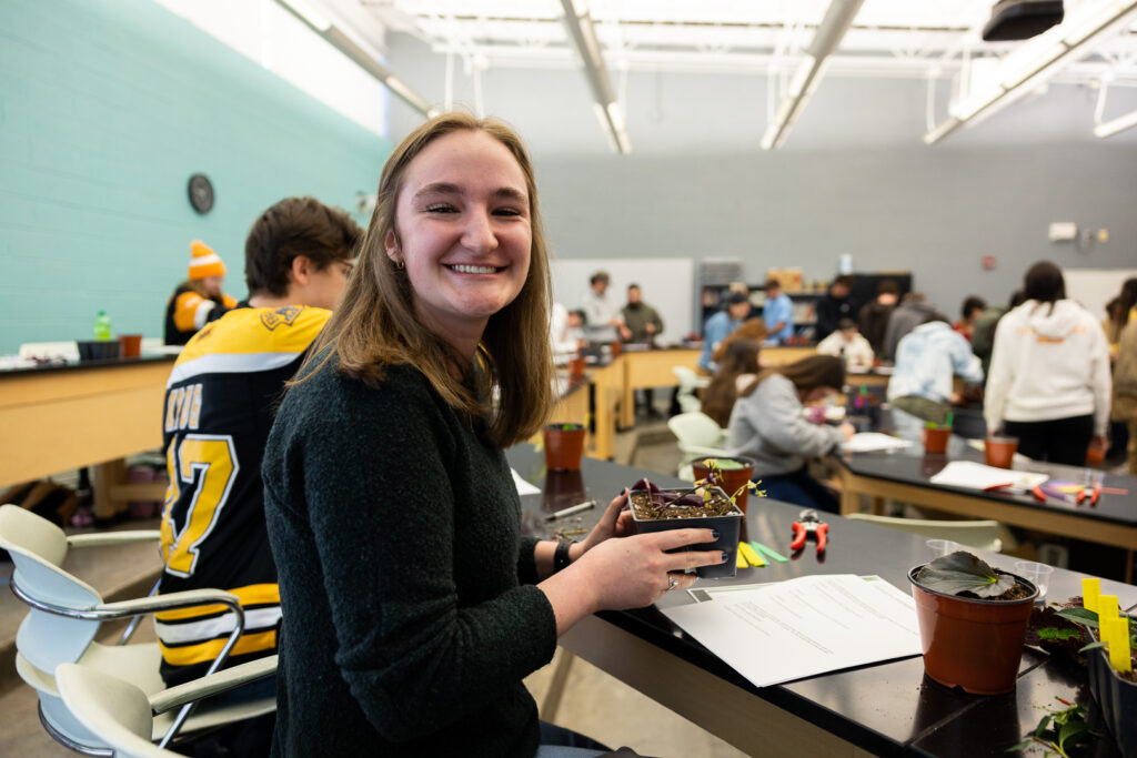 Student holding a plant in class