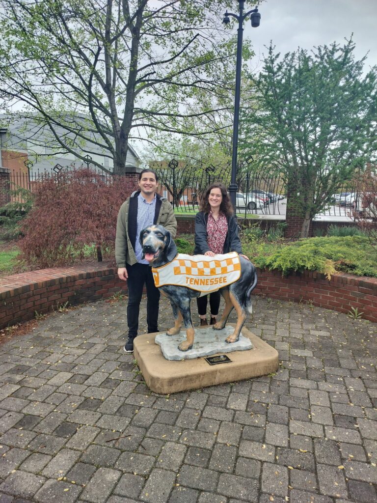 Two students posing by a statue of Smokey