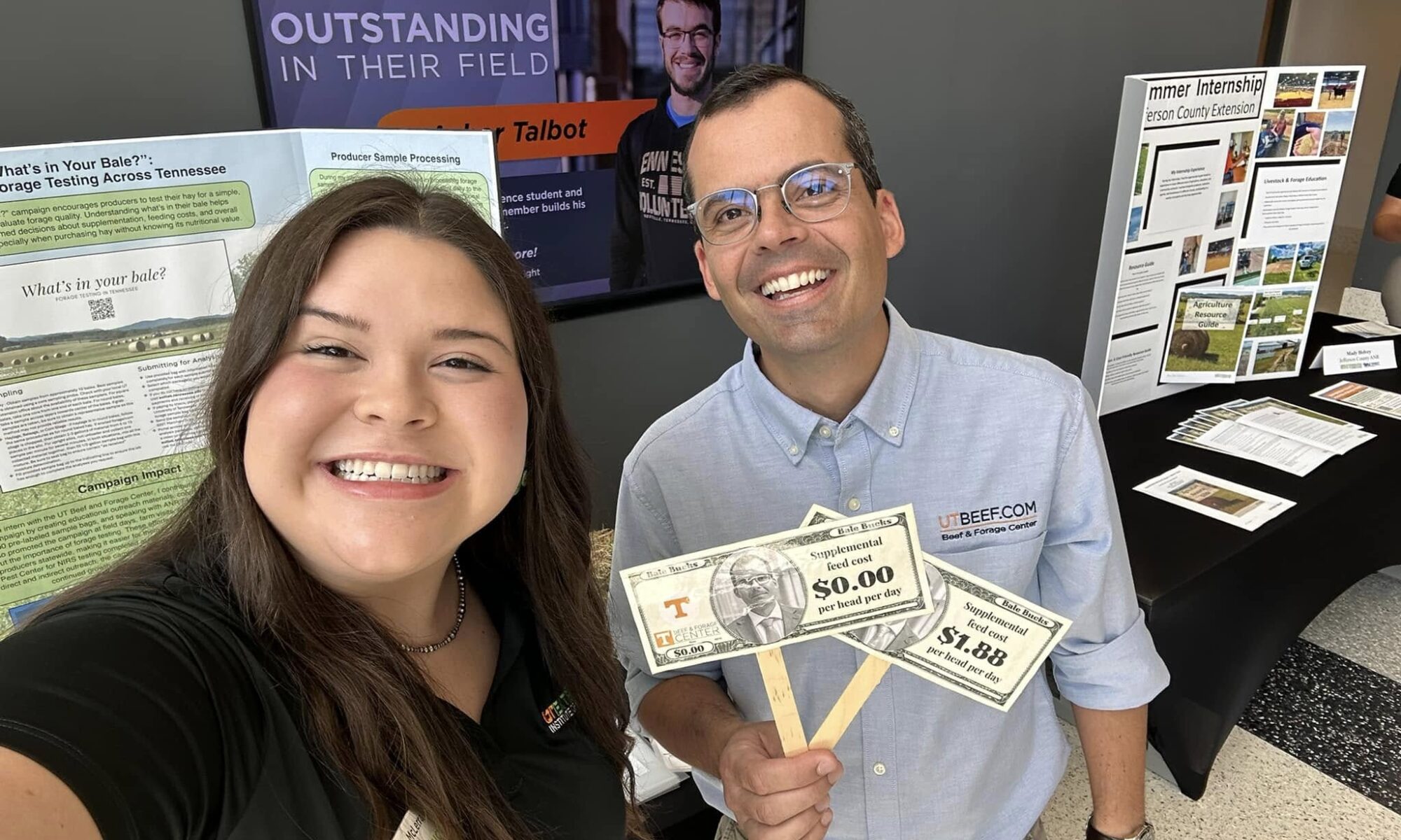 Woman and man smiling at the camera holding up fake money