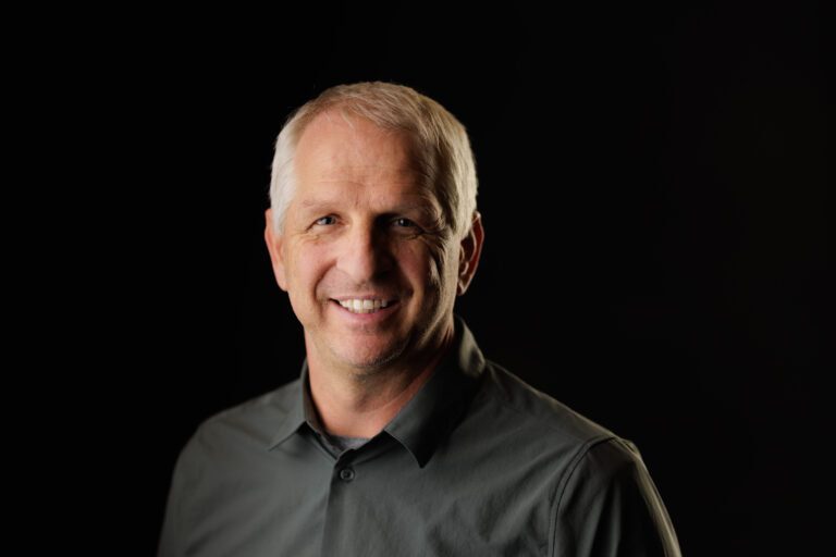 Photo of a man smiling with a black background