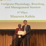 Man and woman posing on a stage holding an award