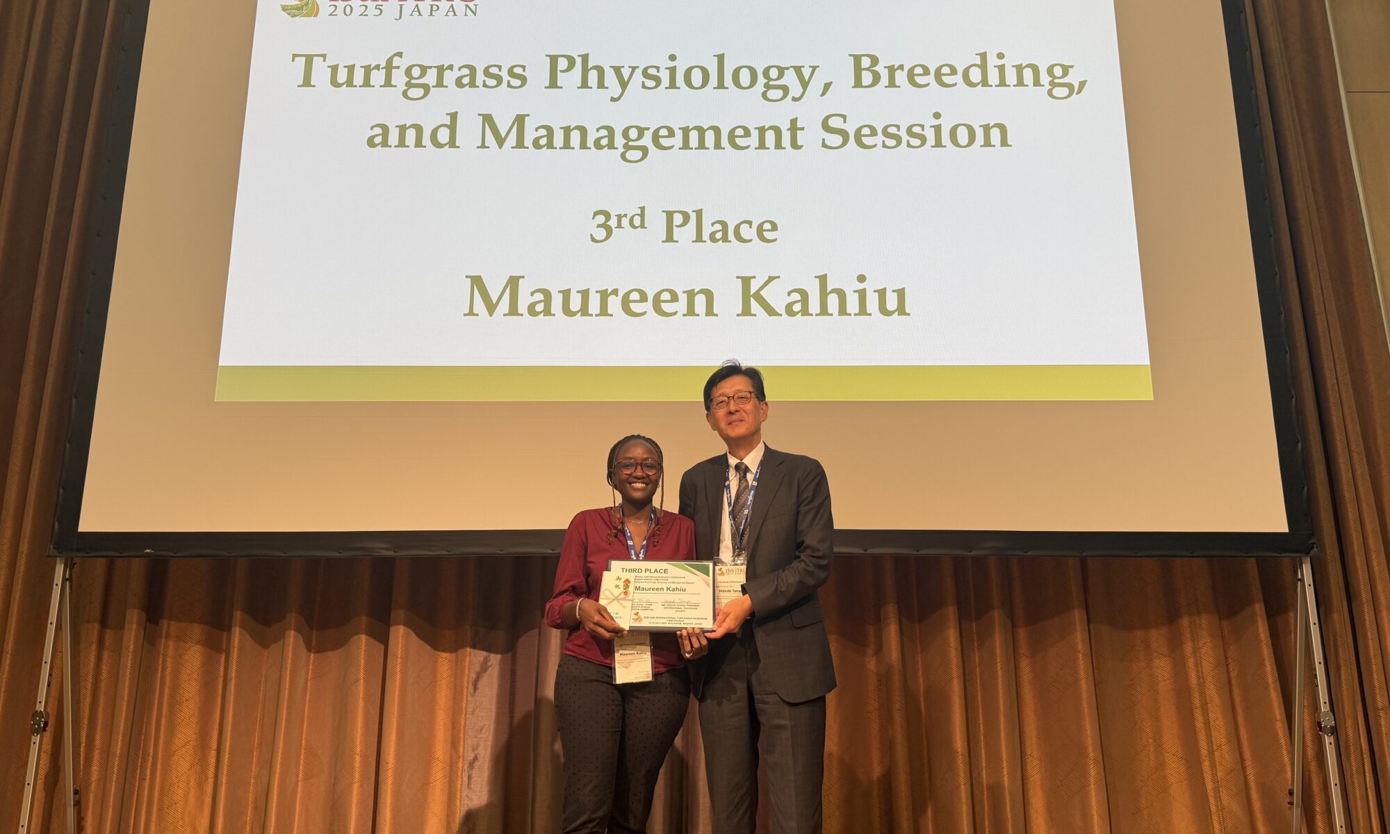 Man and woman posing on a stage holding an award