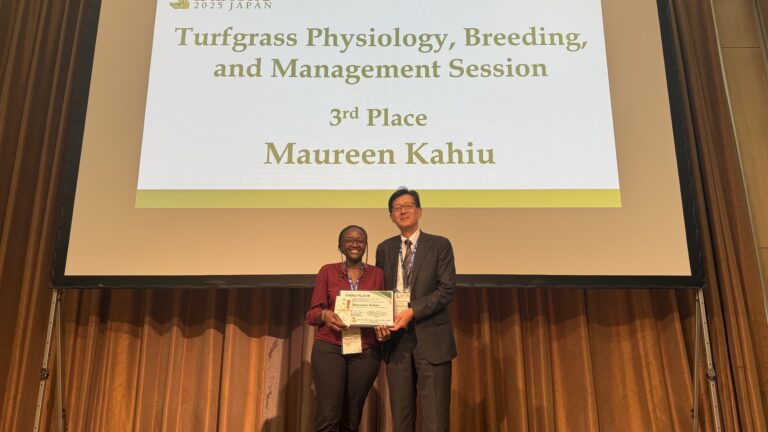 Man and woman posing on a stage holding an award