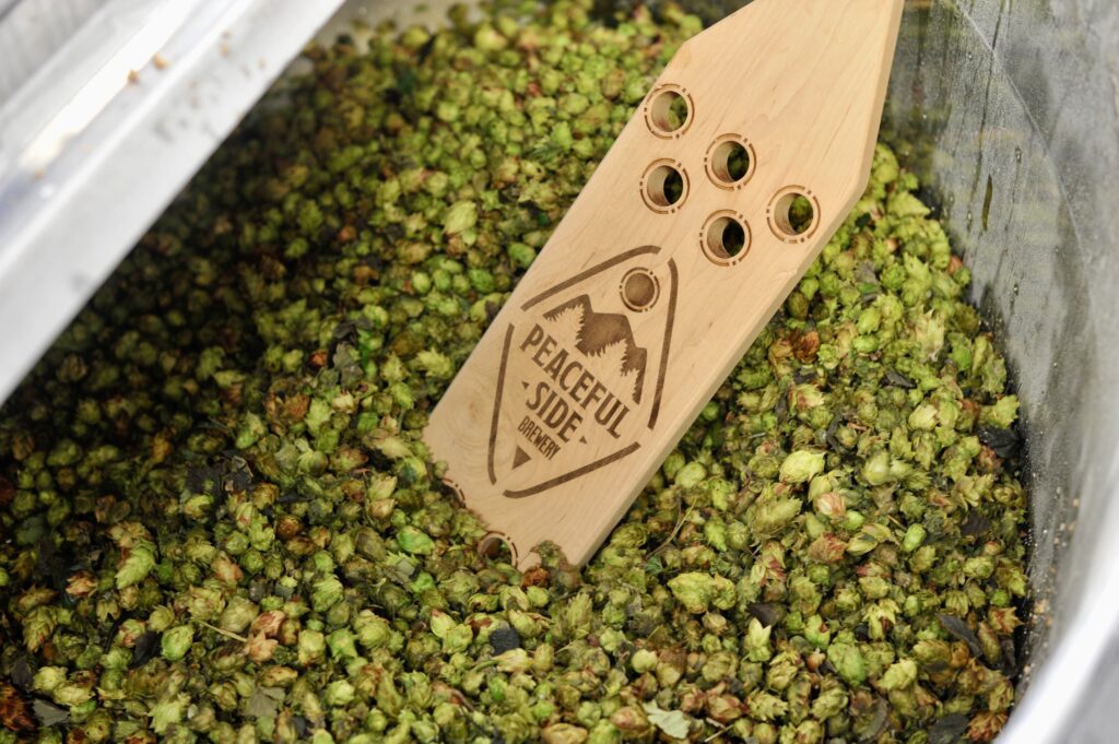 Photo of hops with Peaceful Side Brewery wood in the middle