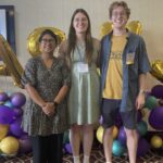 Photo of three people smiling in front of balloons