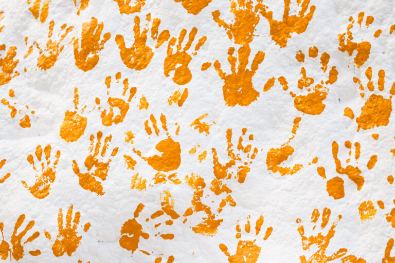 Orange handprints on a white rock