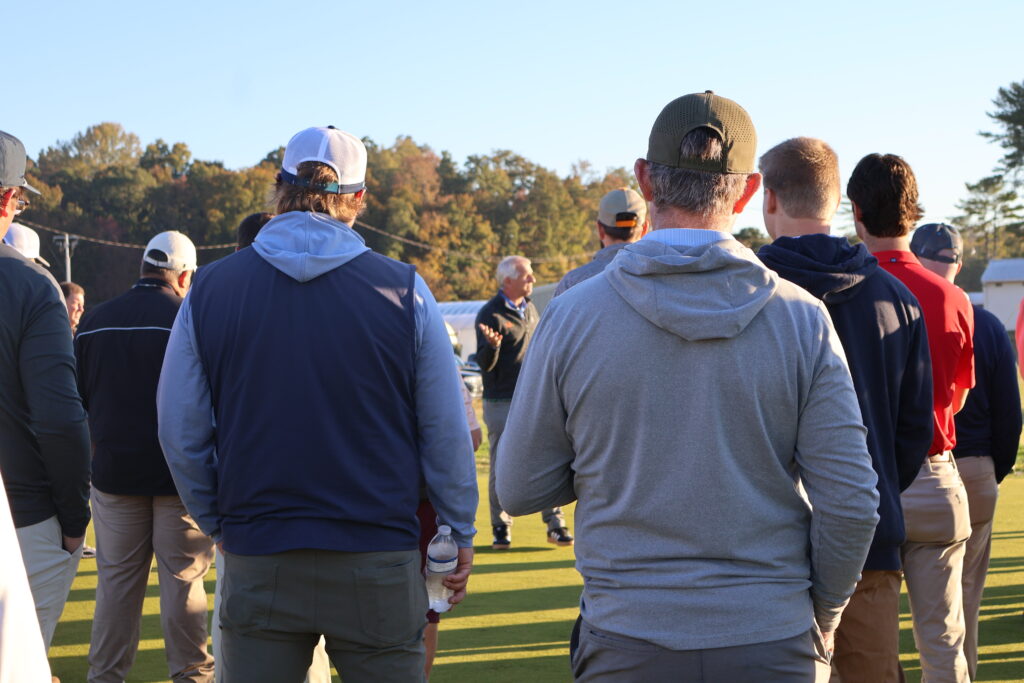 Backs of a group of people listening to a presentation outside