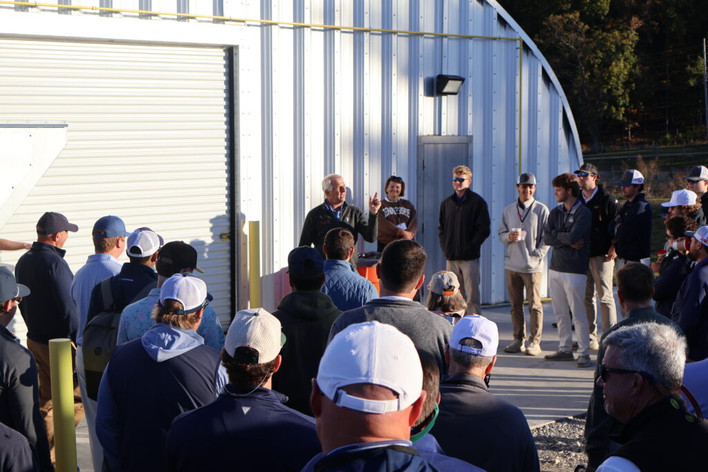 Group of people listening to a presentation in front of a metal building