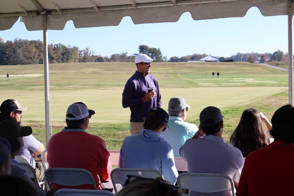 Man talking to a group of people under a tent