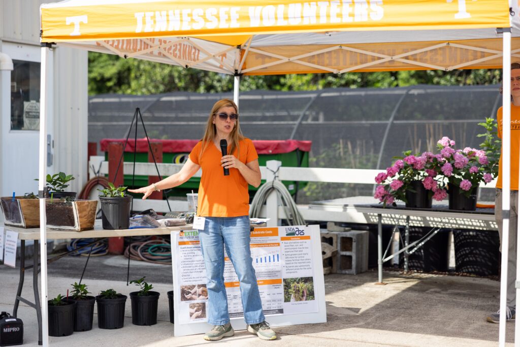 Woman talking in front of a tent of plants