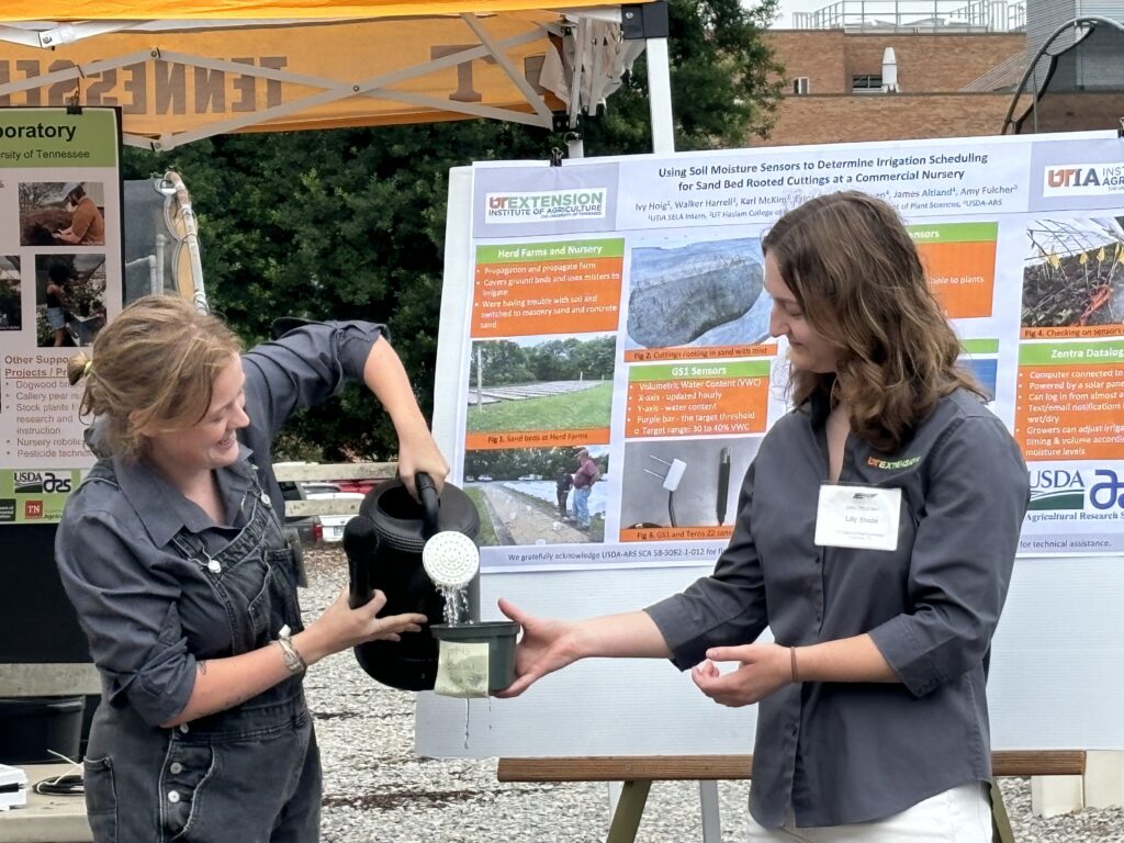 Woman watering a pot and another woman helping her
