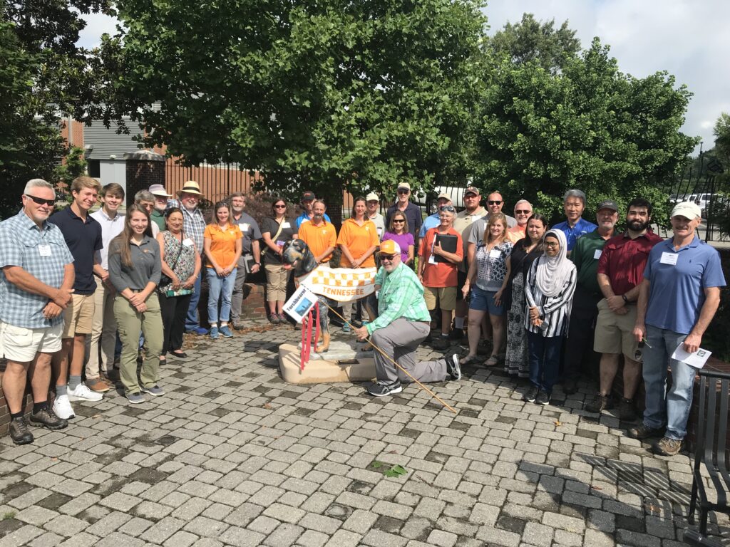 Group of people smiling standing near a Smokey statue