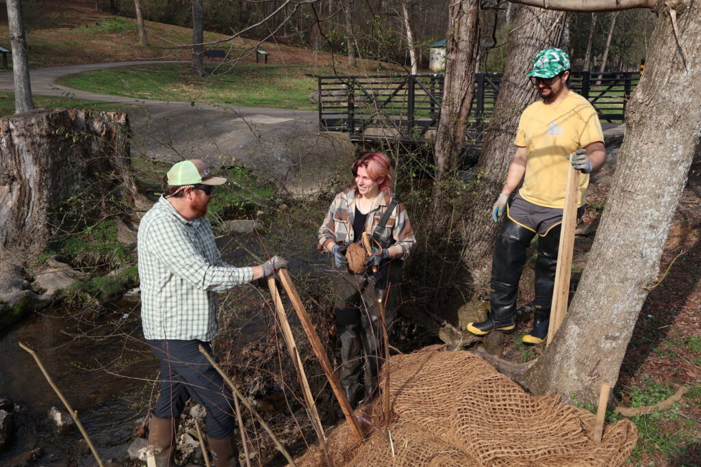 People standing near a woody streambank