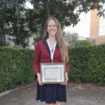 Woman standing outside holding an award