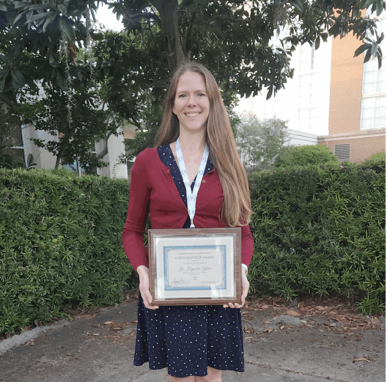 Woman standing outside holding an award