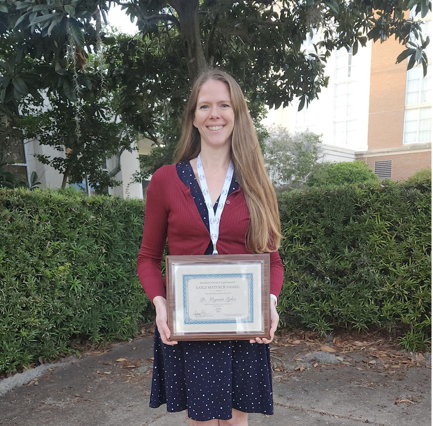 Woman standing outside holding an award
