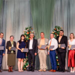 Photo of people standing on a stage with awards smiling