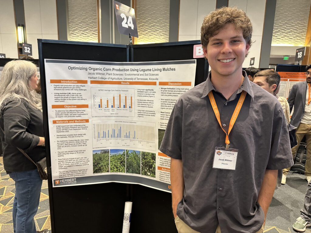 Student standing in front of a poster smiling