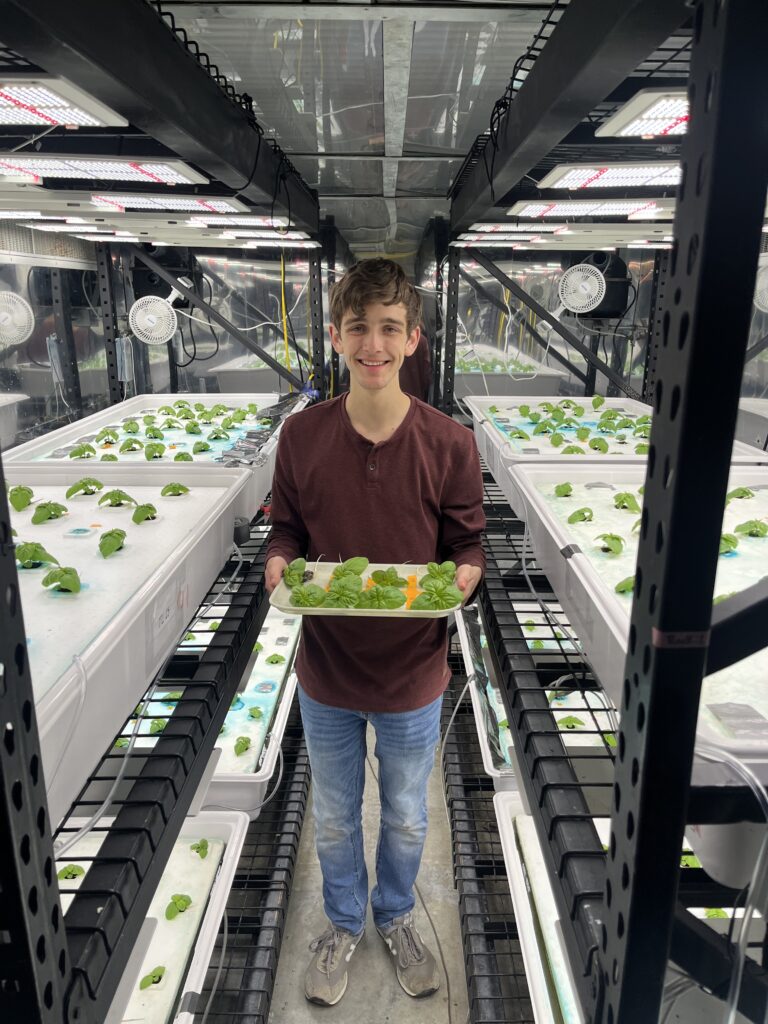 Photo of a student holding leafy greens standing in a lab