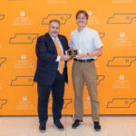 Student standing in front of an orange UT backdrop with Dean White