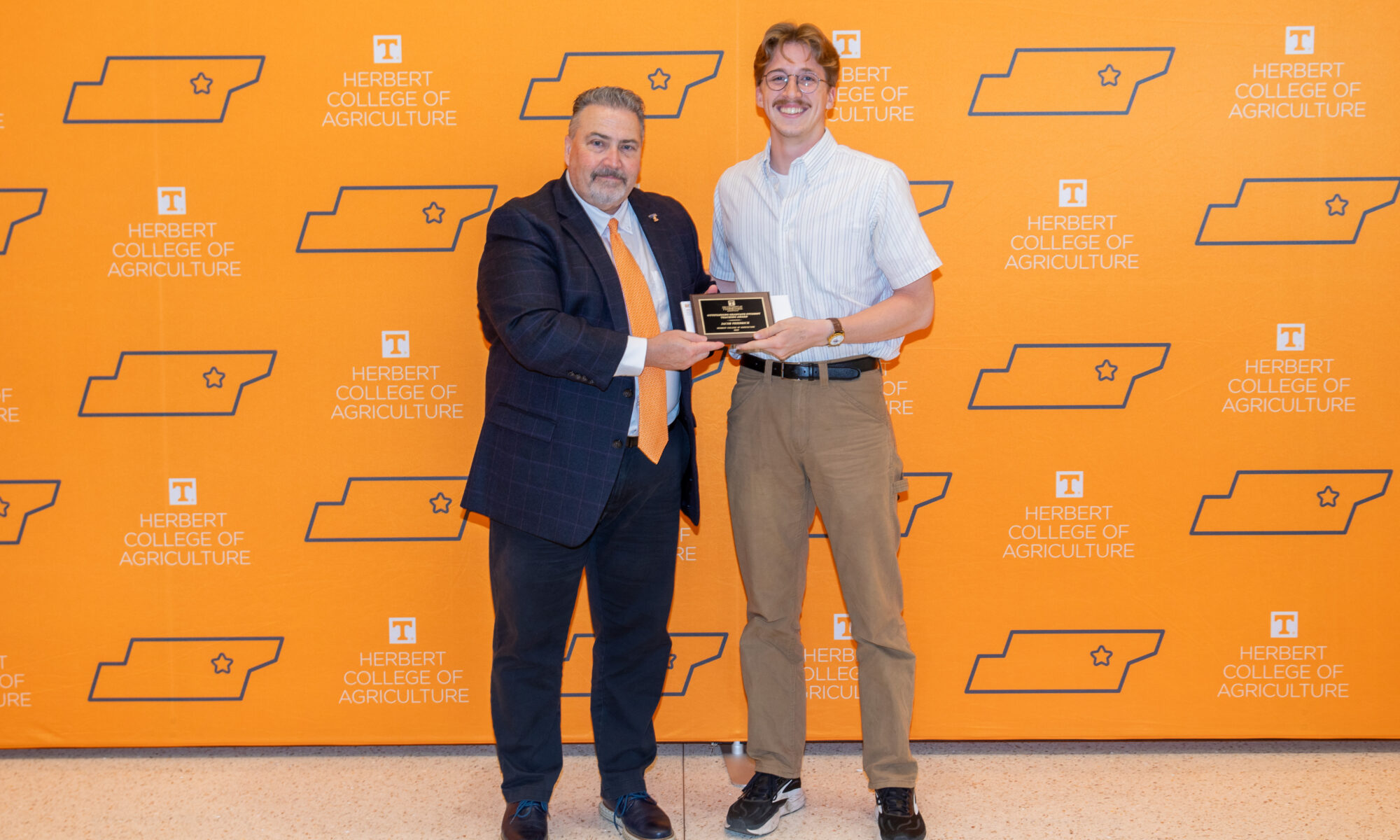 Student standing in front of an orange UT backdrop with Dean White