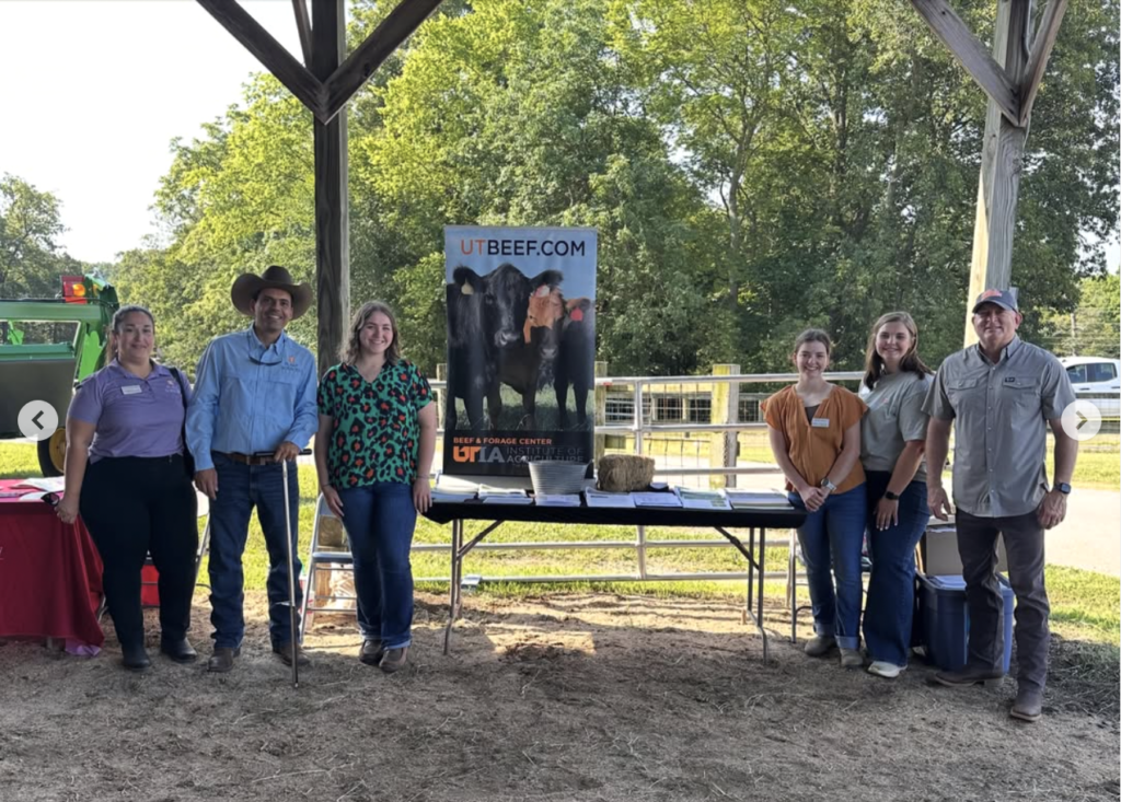 Group of people smiling in front of a table with papers and a UT Beef pull up banner on it