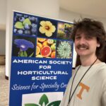 Photo of a man standing next to an American Society for Horticultural Science poster smiling