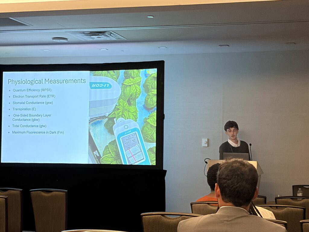 Man standing next to a presentation on a big screen with an audience watching