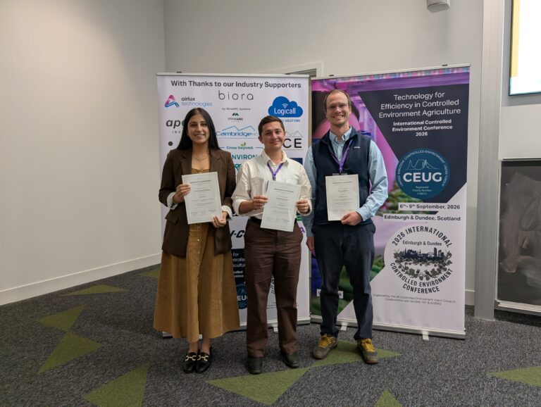 Three people standing in front of pull up banners holding awards