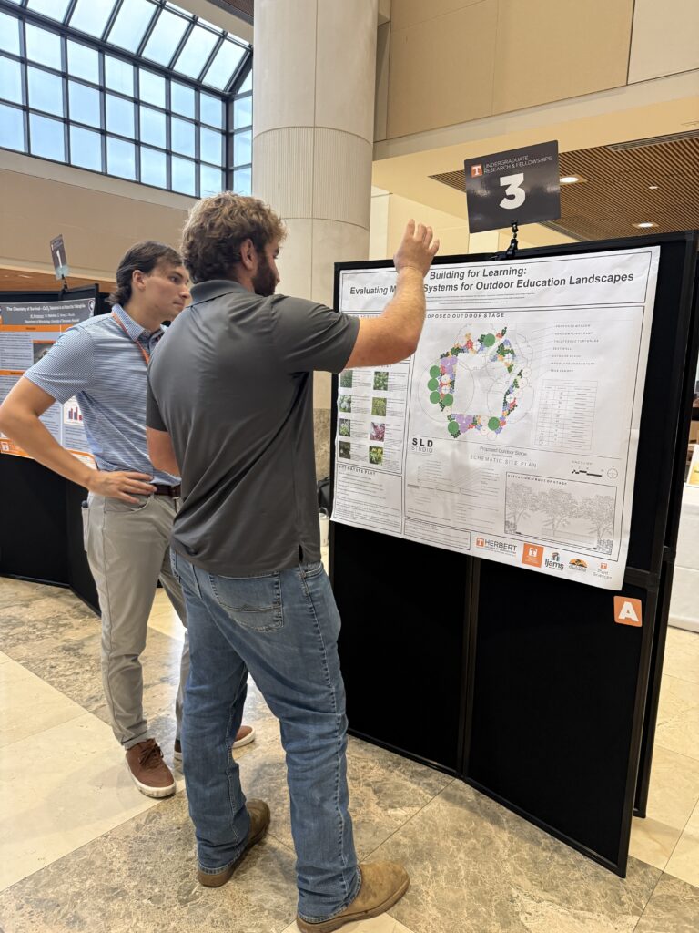 Man standing in front of a poster talking to another man